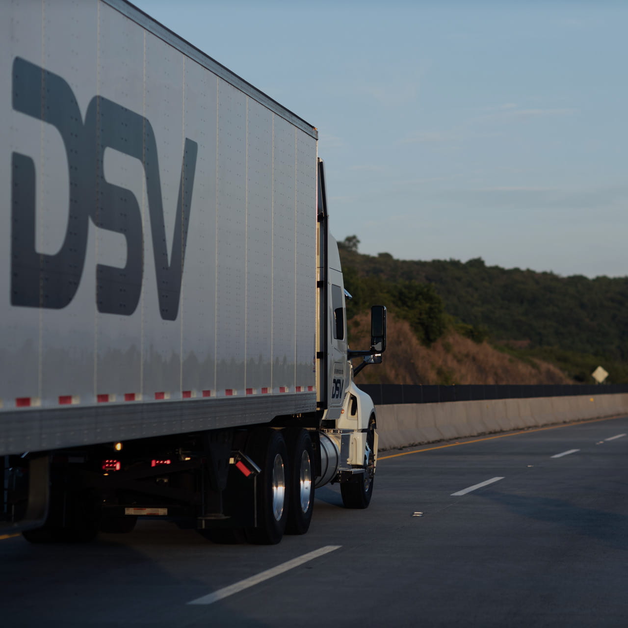 DSV semi-truck traveling on a highway, captured from a side angle focusing on the rear part of the trailer and the cab